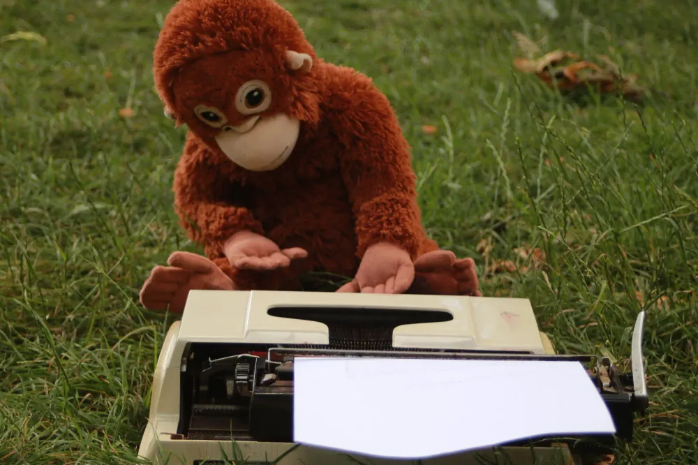 A toy orangutan sitting at a typewriter in the grass, a blank sheet of paper in the roller